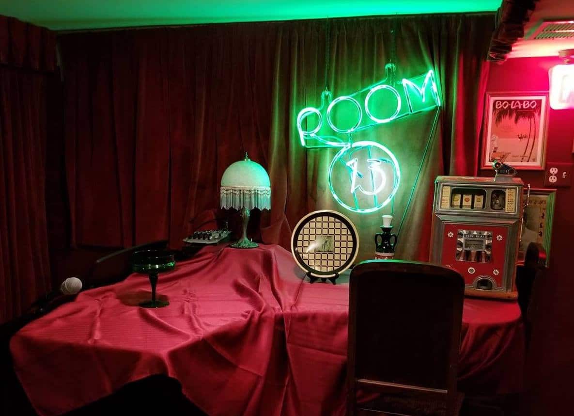 Room 13 neon sign within dark room and red tablecloth on table